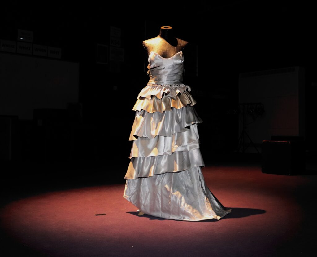 A silver coloured dress with ruffles on a mannequin 