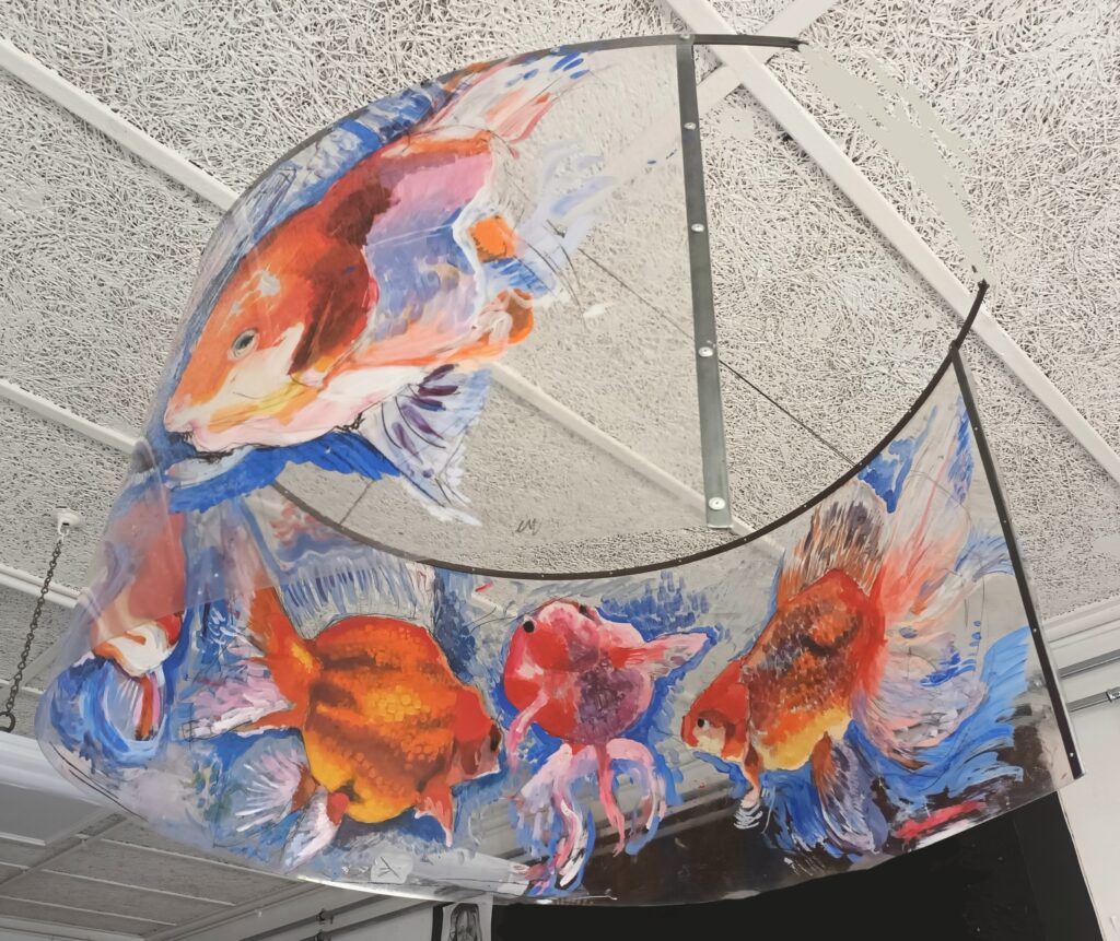 A hanging painting on round perspex of goldfish swimming 