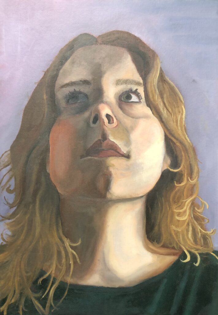 Portrait of a young woman with blonde long hair, wearing a green shirt, she is looking up from the viewer