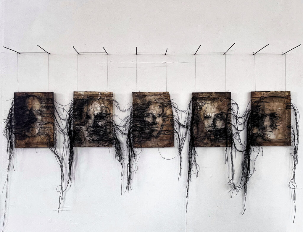 A series of five portraits displayed in a row, each rendered on textured surfaces with black thread stitched across the faces and extending outward, creating a layered, hanging installation.